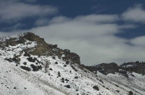 Snow-covered mountain with rocky peaks and cloudy sky.