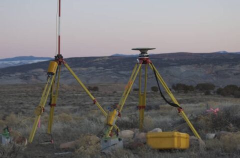 Surveying instruments on tripods in a desert landscape.