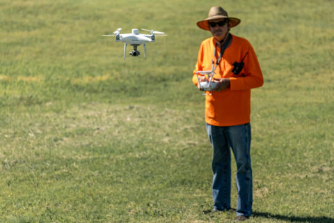 Surveyor operating drone for land mapping in open field.