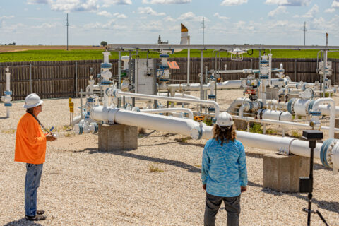 Two surveyors inspecting pipeline infrastructure at a utility site.