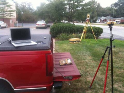 Surveying equipment on a tripod and laptop at a construction site.
