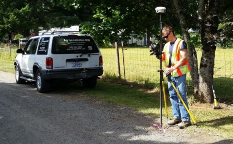 Surveyor with GPS and measuring tools near survey vehicle.